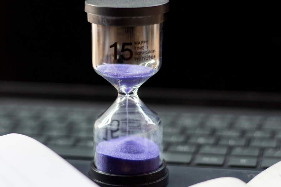 A photo of a sand timer with purple sand, displaying a black number 15 on the side in a dark room.