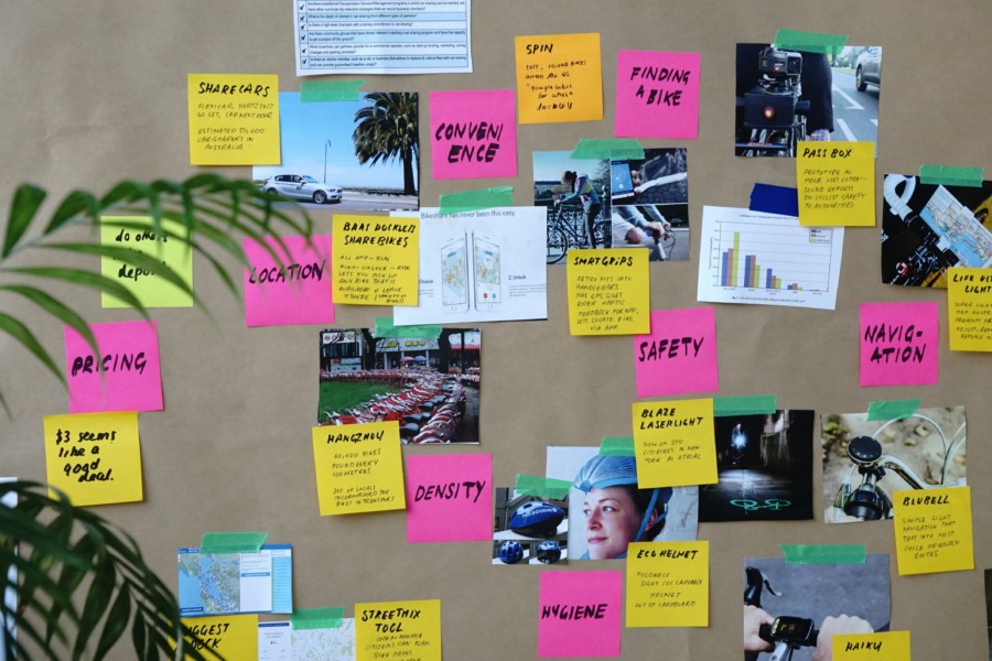 A colourful series of overlapping post-it notes and images pinned to a cork pinboard.