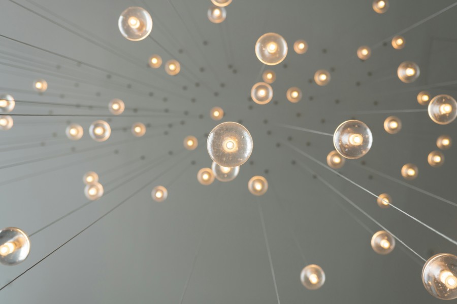 A photo taken from beneath lots of bare lightbulbs hanging from small wires from a white ceiling above.