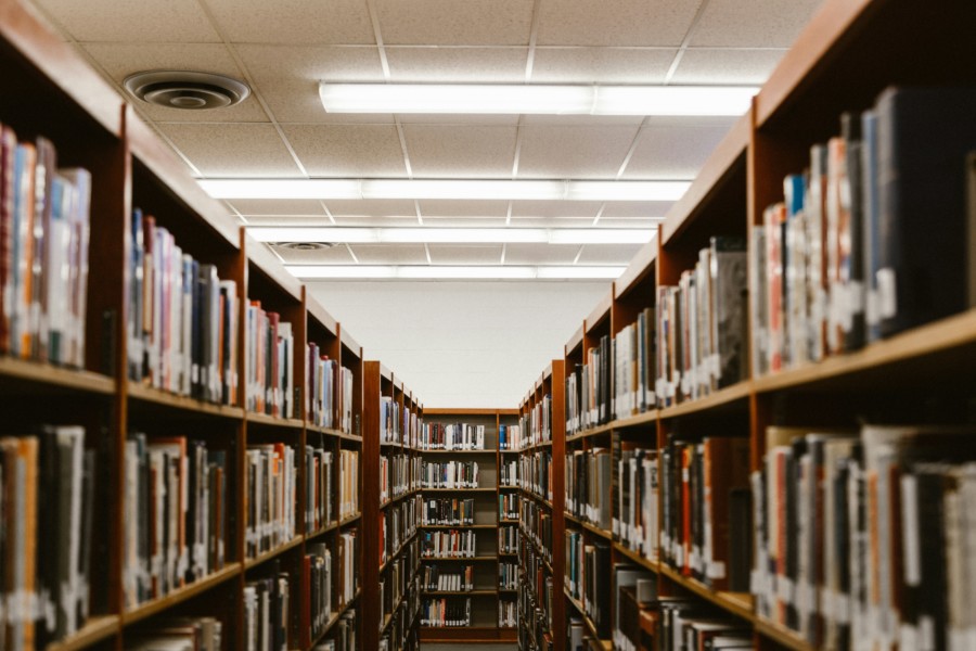 A photo of a library full of books viewed down an aisle from a vanishing point perspective