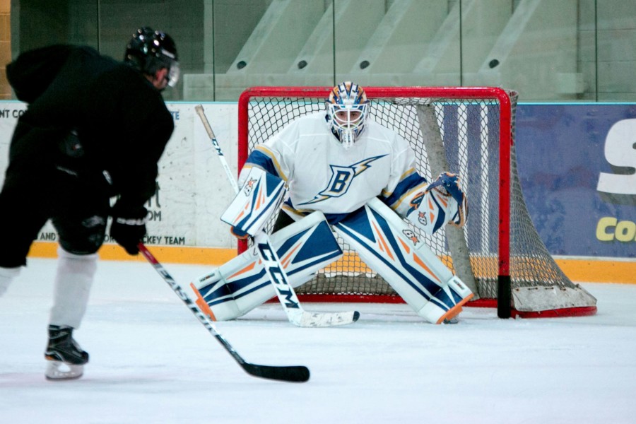 A photo of an ice hockey player squaring up to the goalkeep and goal.