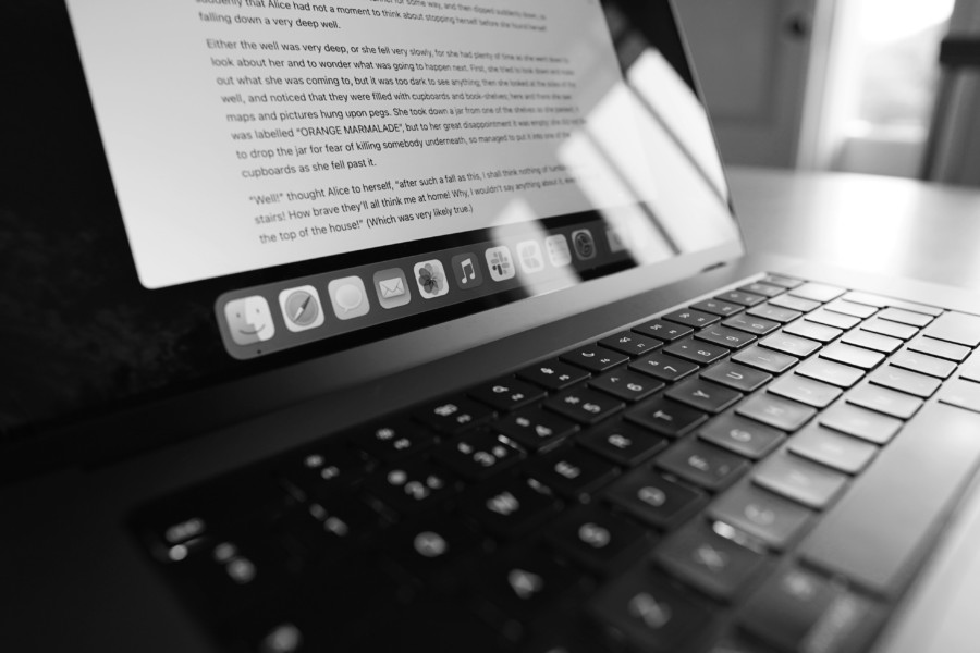 A black and white photo of a laptop, open on a document full of text.