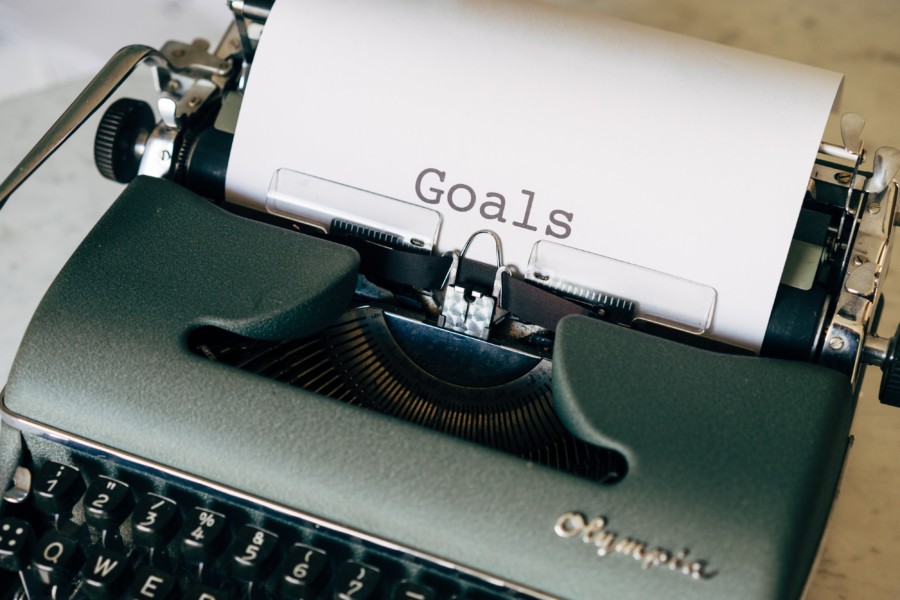 An old typewriter with some paper left in the top that has the word "goals" writtern in the centre, freshly typed.