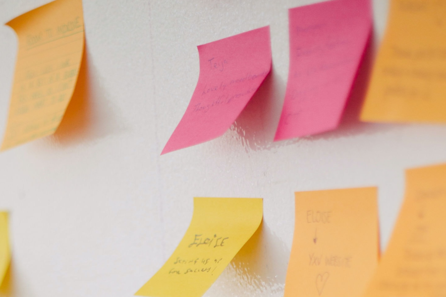 Brightly coloured post-it notes stuck loosely to a whiteboard with short notes handwritten on each