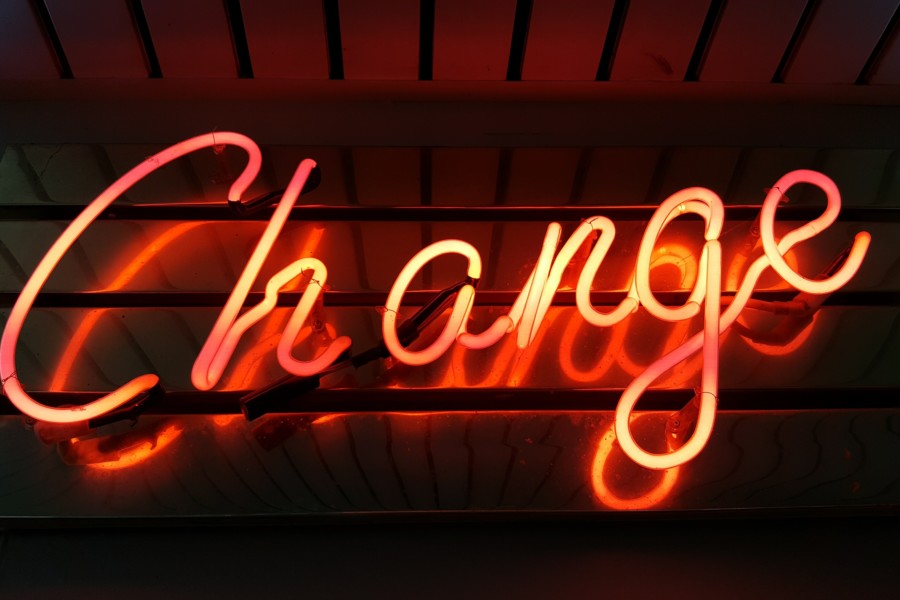 Red neon sign on a wall spelling out the word "Change" in cursive handwritten font.