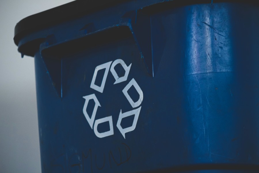 A photo of a dark blue recycle bin with the white outline of the 3 arrow in a triangle symbol.