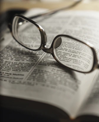 A pair of glasses is upturned on an open book