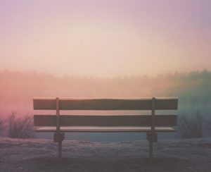 A bench looking out to a purple / orange hazy sunset.