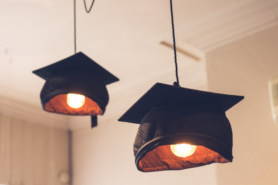 Mortar board graduation hats are wired to form pendant lights hanging from the ceiling