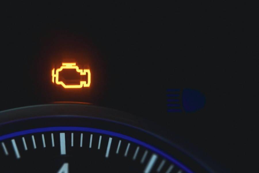 An orange fuel light illuminates a dark vehicle dashboard.