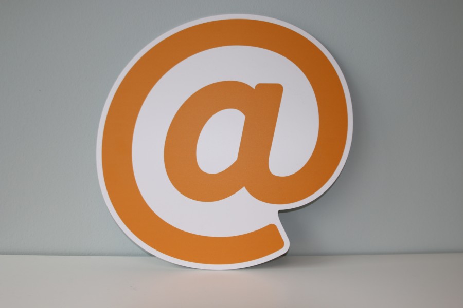 An orange @ symbol plaque leaning up against a white background