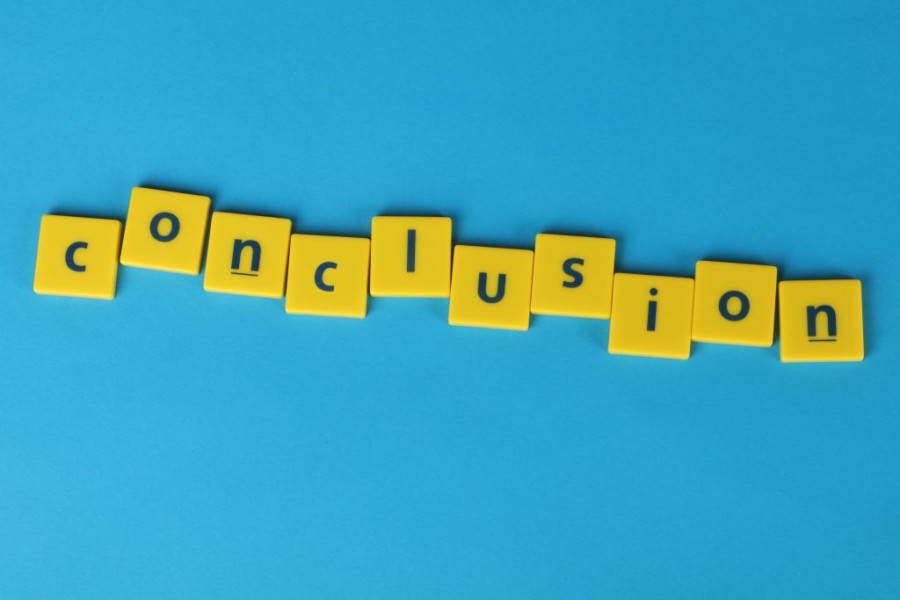 A photo of the word conclusion formed from lettered yellow tiles on a bright blue background.